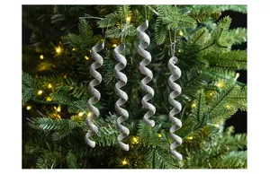 Primer plano de cuatro adornos de carámbanos en espiral plateados en un árbol de Navidad