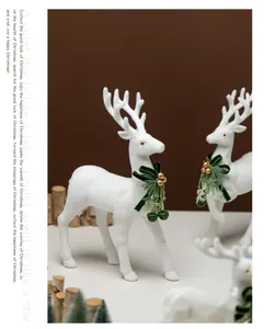 Primo piano di renna floccata bianca con fiocco verde e campanella dorata natale.