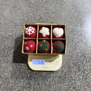 Set de bolas de Navidad de fieltro hechas a mano en una báscula que indica un peso de 51,6g