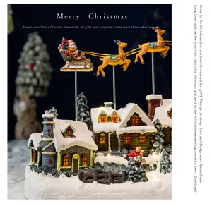 Close-up of illuminated Christmas village resin house with flying Santa reindeer sleigh.