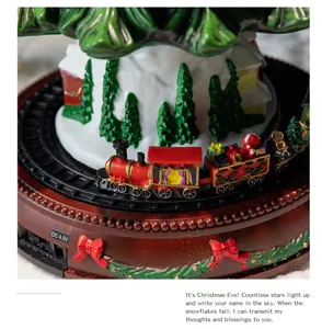 Detail van een roterende miniatuurtrein in een besneeuwd kersttafereel met huisjes.
