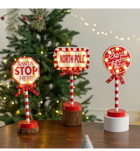 Set of three festive Christmas wooden road signs with warm LED lights on a wooden table