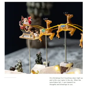 Detailed view of resin flying reindeer and Santa sleigh in glowing Christmas village.