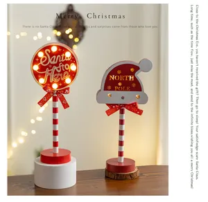 Festive detail of Christmas wooden LED light ornaments with glowing Santa Stop Here sign