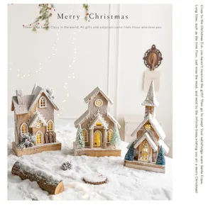 Festive set of three glowing snow-covered wooden Nordic Christmas houses for tabletop decoration