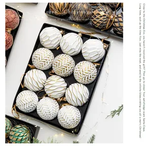Close-up of white and gold Christmas ball ornaments with textured patterns in black tray