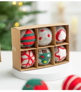 Detalle de 6 bolas navideñas de fieltro hechas a mano en una caja de regalo de papel kraft