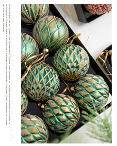 Close-up of decorative 8cm emerald green and gold Christmas baubles with various textures.