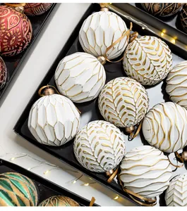 Detail of white and gold Christmas ornaments with intricate relief patterns in a tray.