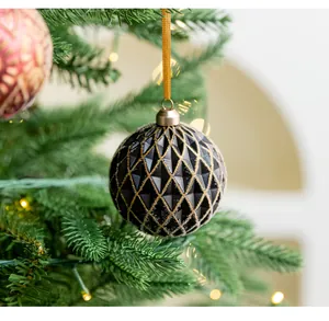 Detailed view of a black Christmas bauble with gold diamond textures on a festive tree