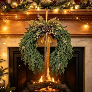 Élégante couronne de Noël bohème avec pommes de pin et ruban doré sur cheminée