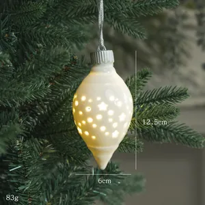 Adorno navideño de cerámica luminosa con recortes de estrellas en una rama de pino