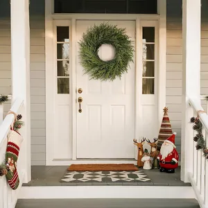 Couronne de pin Norfolk verte sur une porte d'entrée blanche pour les fêtes de Noël.