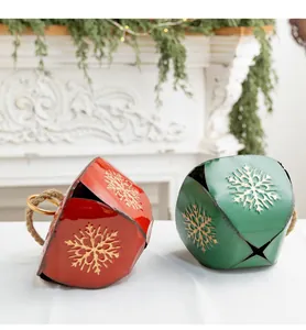 Détail de cloches de Noël vintage en métal rouge et vert avec des flocons de neige dorés.