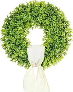 Close-up of artificial green boxwood wreath with elegant cream ribbon for front door decor