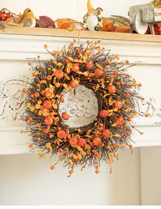 Detailed view of autumn harvest wreath with mini pumpkins and berries on mantel