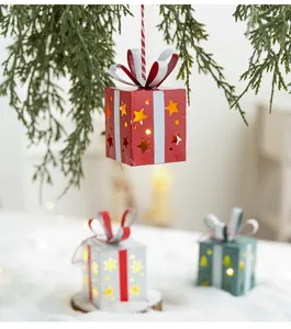Détail de la décoration d'une boîte cadeau en fer lumineuse suspendue au sapin de Noël
