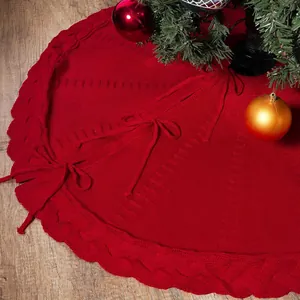 Détail d'un tapis de sapin de Noël en tricot rouge torsadé avec de belles décorations.