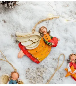 Hand-painted resin angel ornament with red heart detail on snowy background.