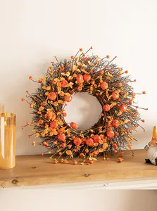 Detailed view of rustic autumn harvest wreath with orange pumpkins and berries on a shelf