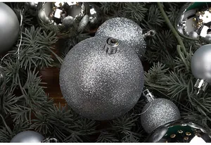 Close-up detail of silver glitter and matte Christmas ball ornaments on pine branches