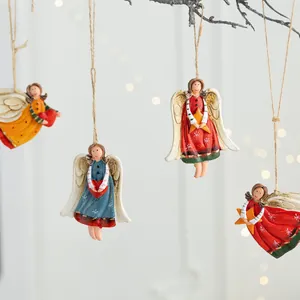 Hand-painted resin angel girl ornaments hanging on branches with warm bokeh lights