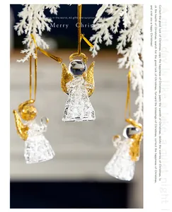 Detailaufnahme von Kristallglas-Engelsfiguren mit goldenem Glitzer auf weißen Zweigen.
