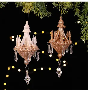 Detailed view of two glittering Christmas chandelier ornaments hanging on a pine branch.