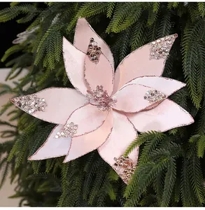 Nahaufnahme einer rosa Seidenstoff-Weihnachtsblume mit Pailletten an grünem Zweig