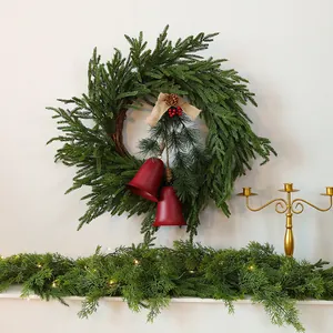 Corona di Natale artificiale con aghi di pino, campane rosse e ghirlanda coordinata.