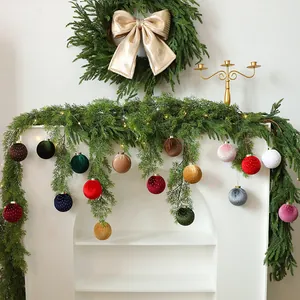 Bolas de Navidad de terciopelo con puntos en una guirnalda sobre una chimenea blanca.