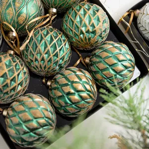 Set of green and gold textured Christmas ornaments in a black display box for holiday decor.