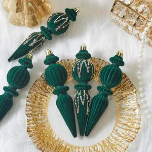 Detail of emerald green flocked Christmas ornaments with gold accents on white fur.