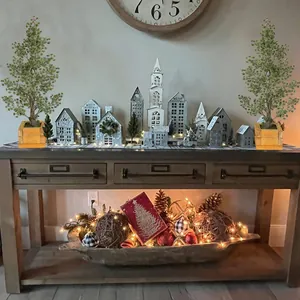 Two artificial potted cedar trees with wooden bases on a festive console table