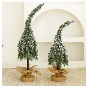 Two green mini bent-top Christmas trees with snowy branches and burlap wrapped bases
