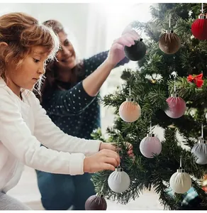 Fluwelen kerstballen in diverse kleuren die door kinderen aan een boom zijn gehangen