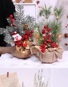 Detailweergave van DIY verlichte kerstminiboompjes met bessen en jute basis.