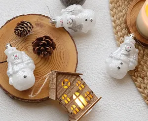 Dettaglio di pupazzi di neve glitterati e decorazione casetta in legno luminosa