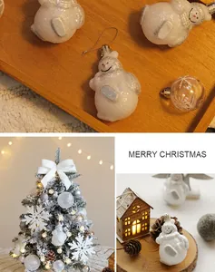 Dettaglio di addobbi natalizi a forma di pupazzo di neve bianco glitterato su vassoio