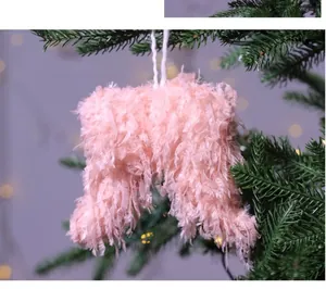 Primer plano de un adorno de alas de plumas rosas colgado en la rama de un pino