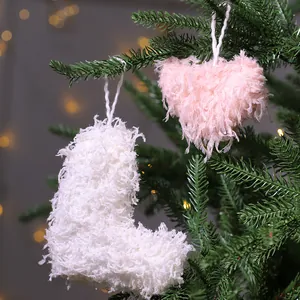 Corazón rosa suave y adornos de calcetín de plumas colgados en un árbol de Navidad