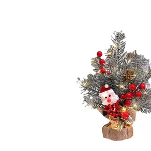 Miniatuur verlichte kerstboom met kerstman decoratie en rode bessen op wit scherm