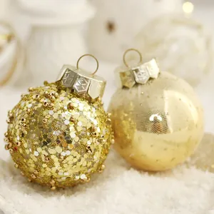 Elegant gold Christmas ornaments with sequins and beads resting on white snowy surface.