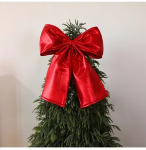 Close-up of a large metallic red Christmas bow decoration on a green tree topper