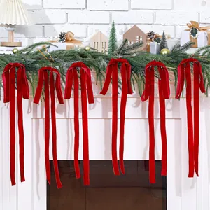 Detail of six elegant red velvet bows hanging from a lush green Christmas garland on a mantel