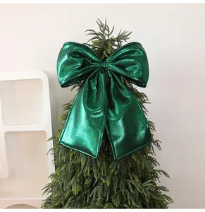 Large metallic emerald green Christmas tree topper bow decoration with shiny foil texture.