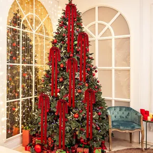 Large red velvet bows with long tails decorating a festive Christmas tree in a cozy room