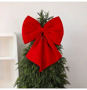 Vibrant red velvet bow decoration featured on the top of a green Christmas tree