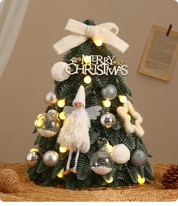 Primo piano di un albero di Natale da tavolo con angelo e calde luci a LED accese.