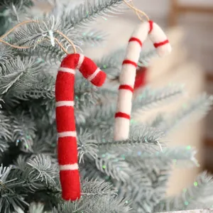 Zwei rot-weiße Zuckerstangen aus Filz hängen an einem gefrosteten Weihnachtsbaum